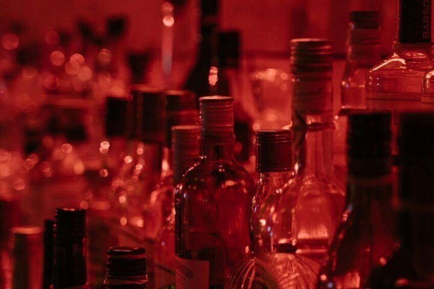 A collection of clear glass bottles with metal caps, likely containing beverages, arranged closely together. 4
