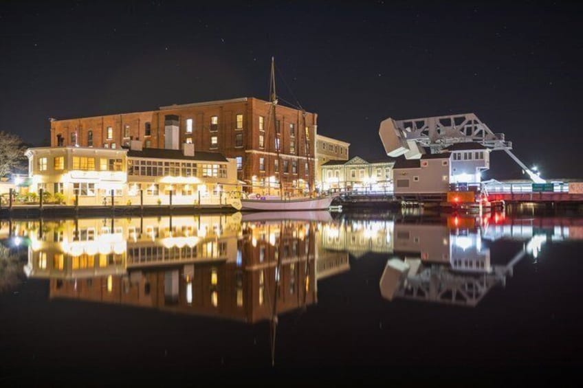 A waterfront with buildings, a docked boat, and a large crane structure. 1