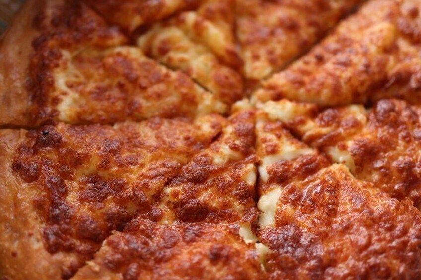 A close-up of a pizza with a golden-brown crust and melted cheese. 5