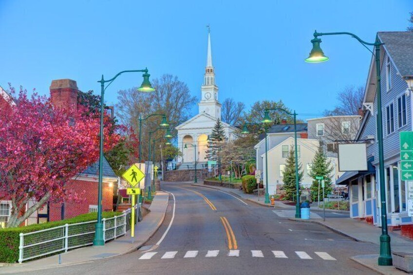 A town street with a church steeple, pedestrian crossing, and storefronts. 2