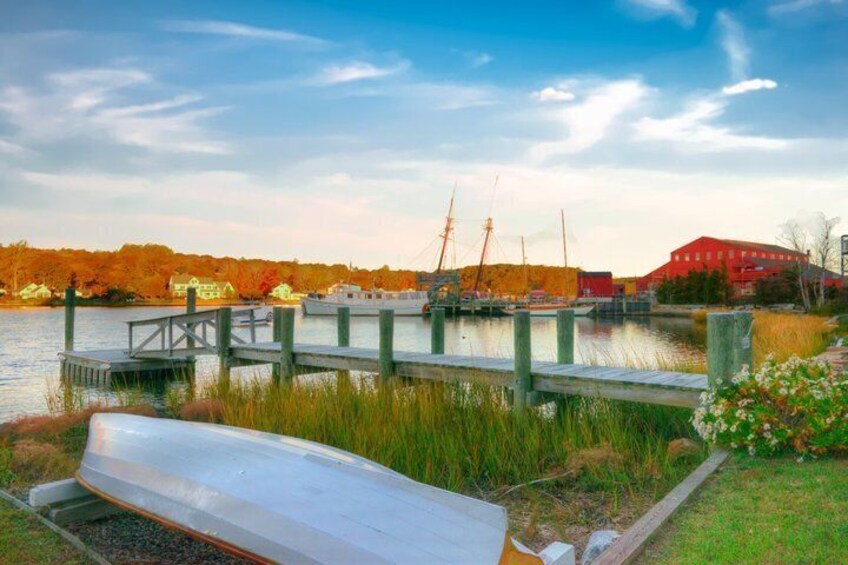 A dock, boats, a red building, and autumn trees by a lake. 3
