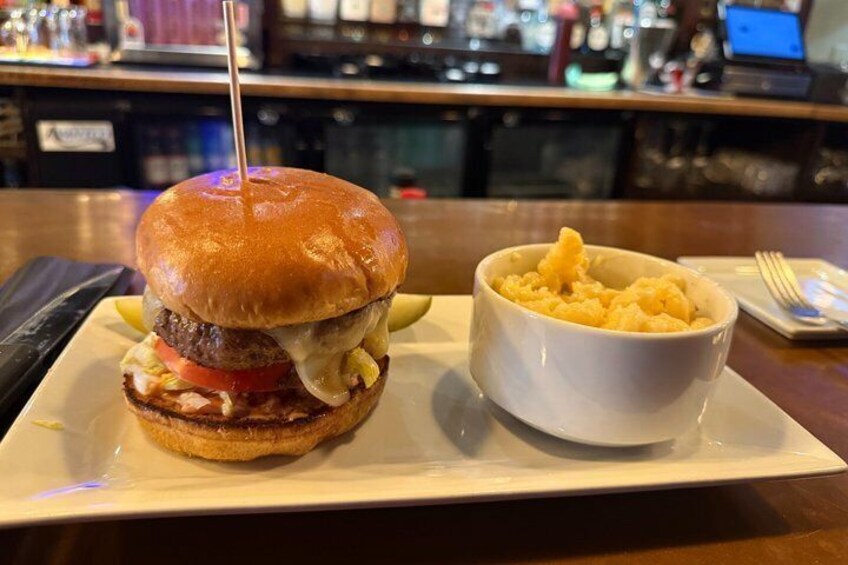 A burger with a toothpick, fries, and a bowl of macaroni and cheese on a plate. 5