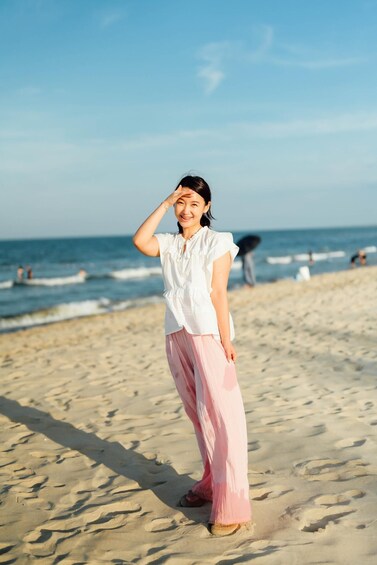A person standing on a sandy beach with the ocean in the background. 4