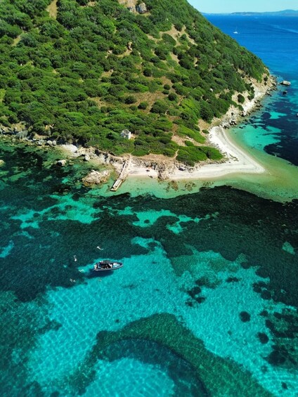 A coastal landscape with a beach, clear turquoise waters, and a boat. 2