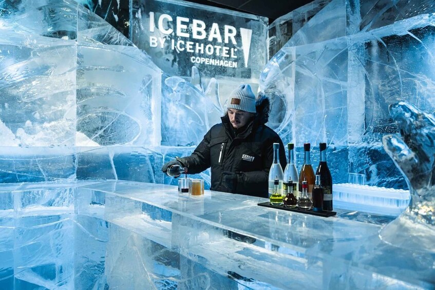 A person at an ice bar with bottles and glasses. 1
