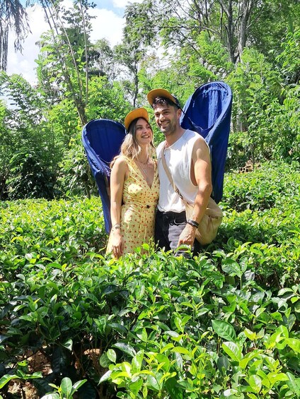 Two people in a garden with lush greenery and a blue structure in the background. 3