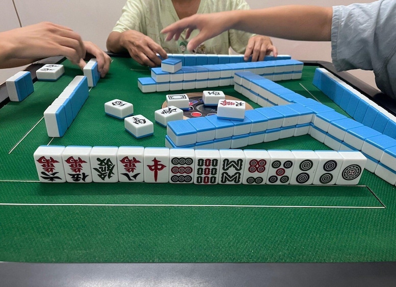 A game of Mahjong with tiles arranged on a green felt table. 1
