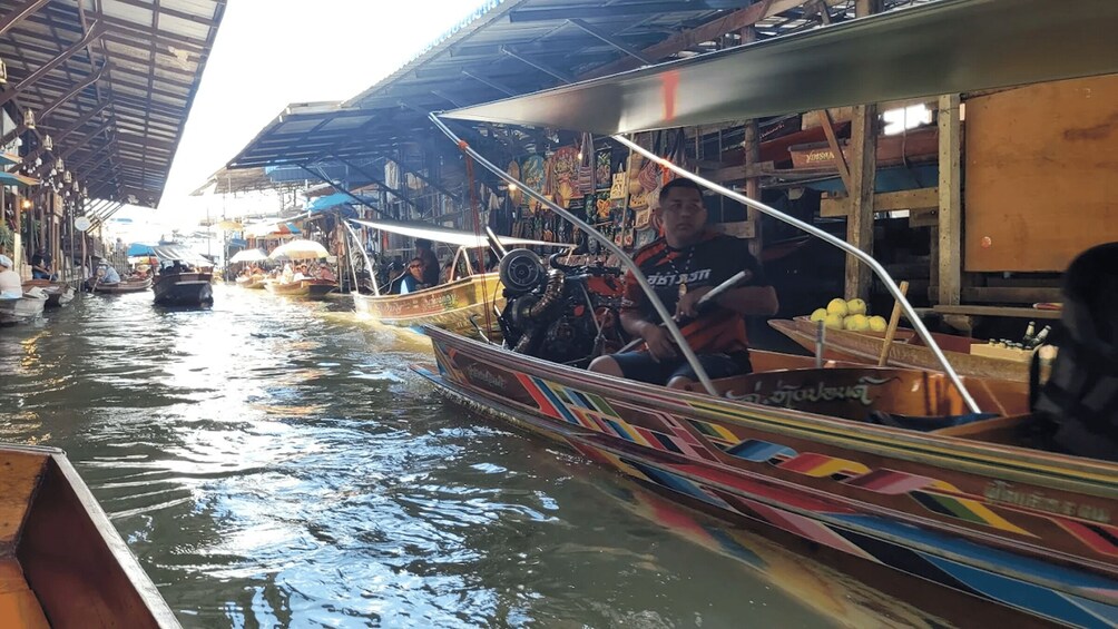 A narrow waterway with boats, a covered market on the right, and a person steering a boat. 4