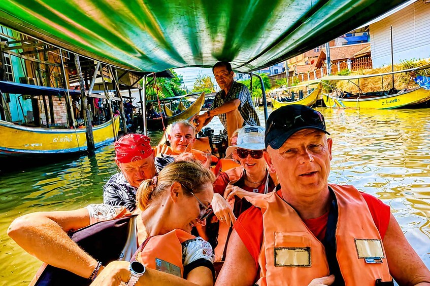 A group of people on a boat, wearing life jackets, with a bridge overhead. 5