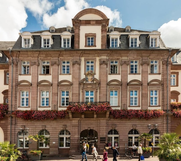 A historic building with a symmetrical facade, arched windows, and a central emblem. 4