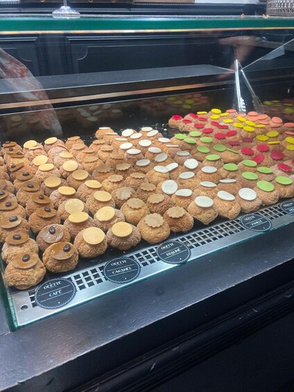 A display case with assorted pastries, including cookies and cakes, some with toppings like chocolate and cream. 3