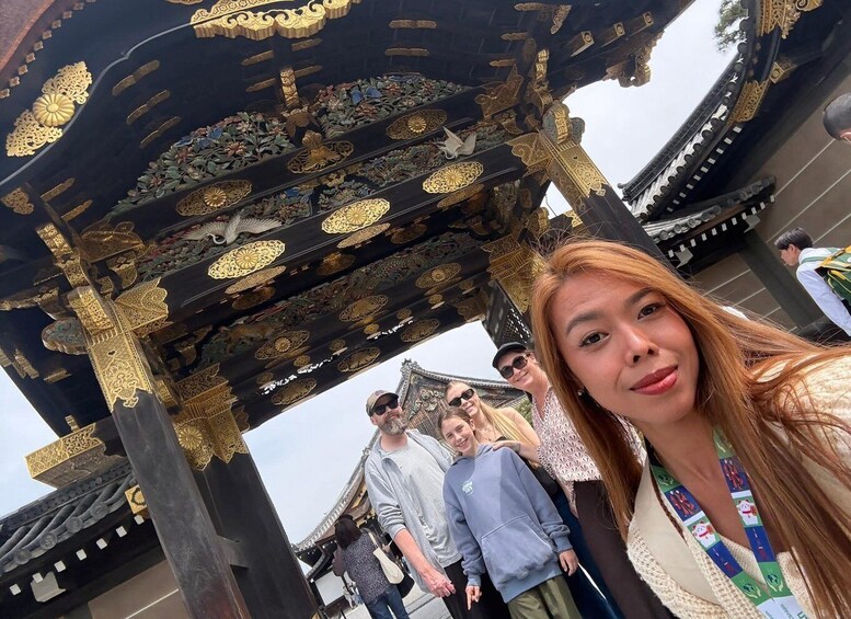 A person taking a selfie under a traditional ornate wooden structure with intricate carvings. 2