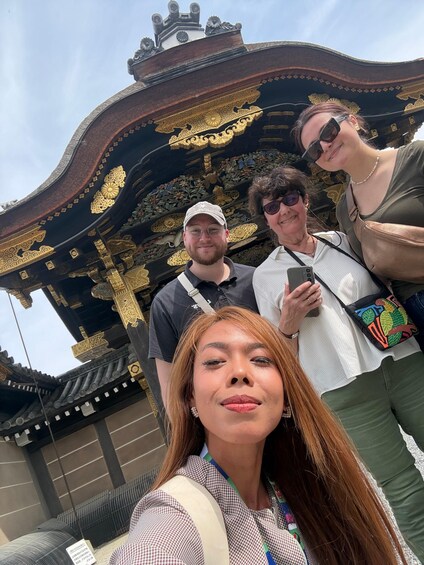 A group of people taking a selfie in front of a traditional building with ornate golden decorations. 4