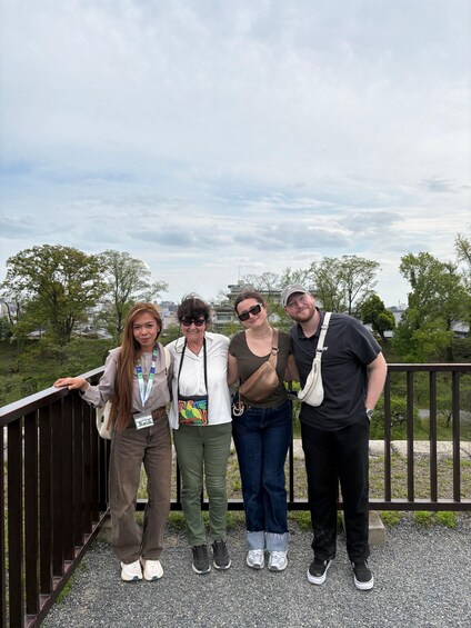 Four people standing on a bridge with a cityscape in the background. 5
