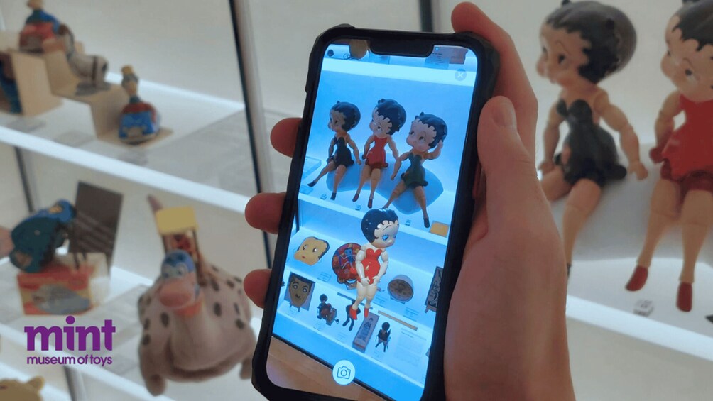 A hand holding a smartphone displaying a museum of toys. 2