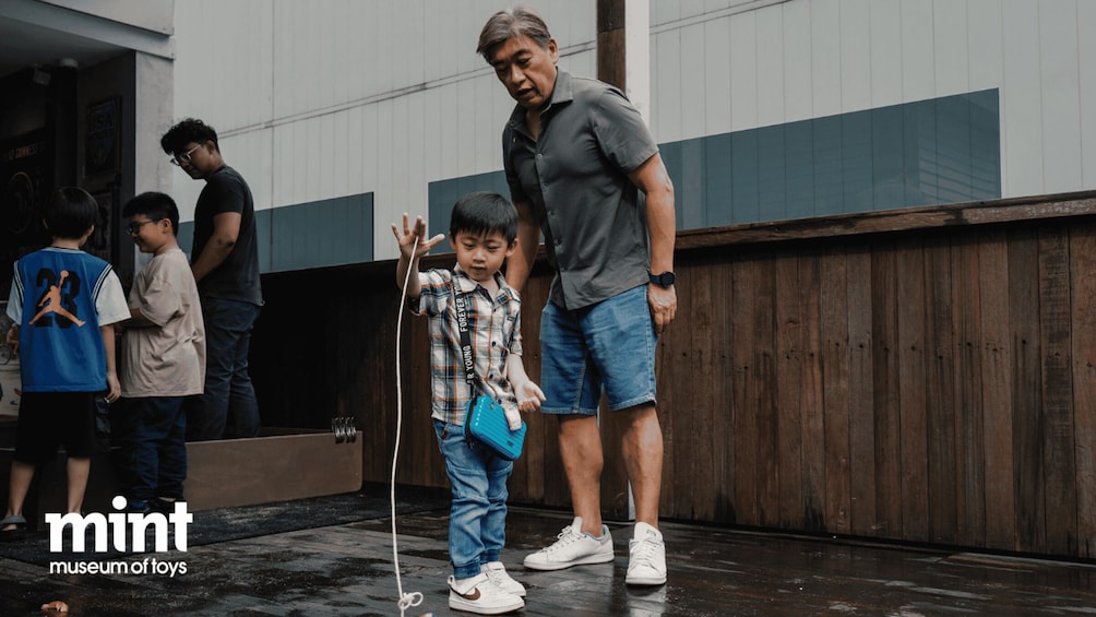 A man and a child with a toy in an outdoor setting, possibly a museum. 3