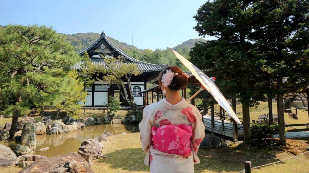 A traditional Japanese building with a tiled roof, surrounded by trees and a pond. 1