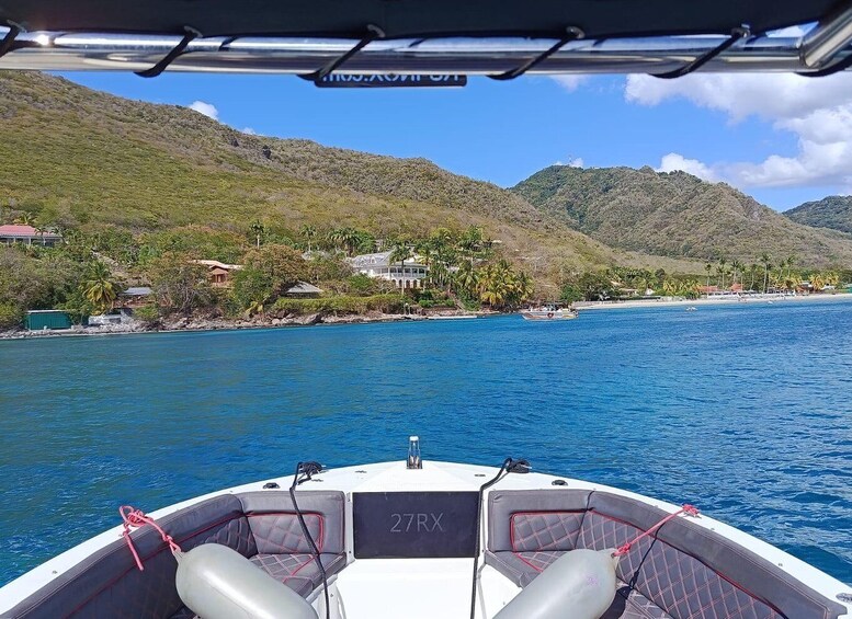 A boat on a calm sea with a coastal landscape in the background, including houses and hills. 5