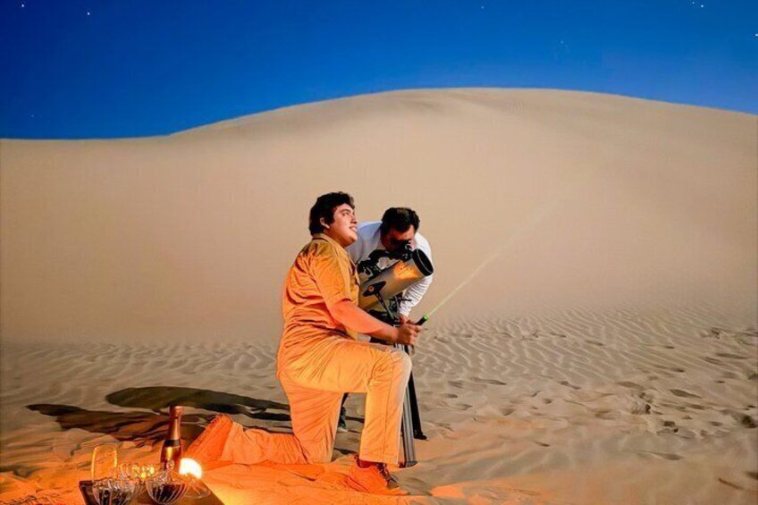 Two people sitting on a dune in a desert at night. 3