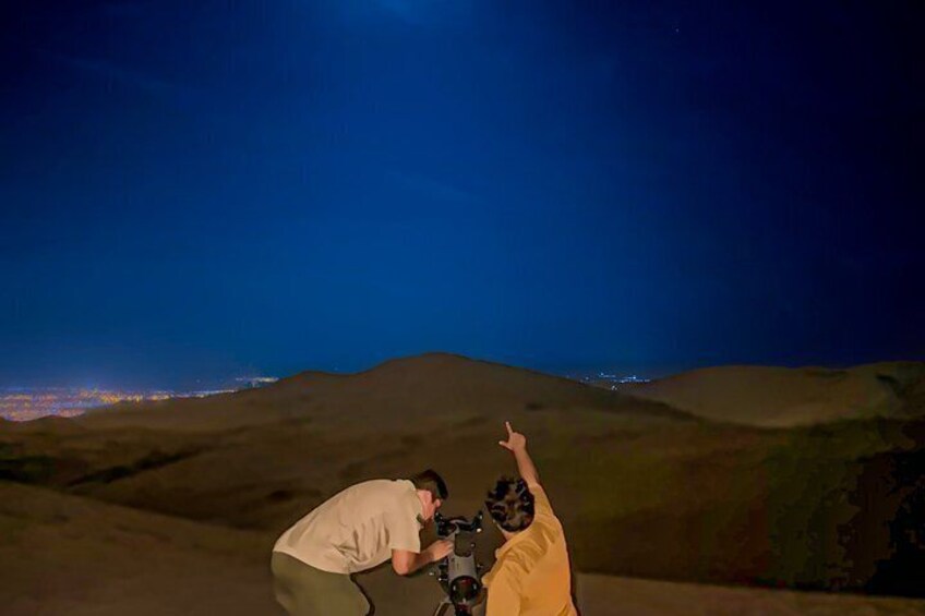 A person taking a photo with a camera in a desert landscape at night. 5