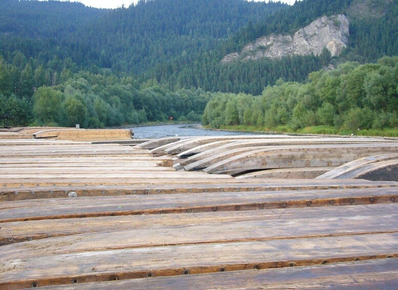 A series of wooden platforms by a river, surrounded by dense forest and hills. 4