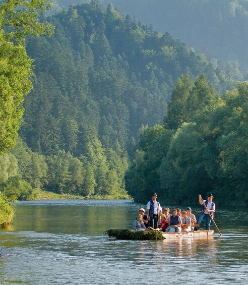 A group of people rowing a boat on a river surrounded by dense forest. 3