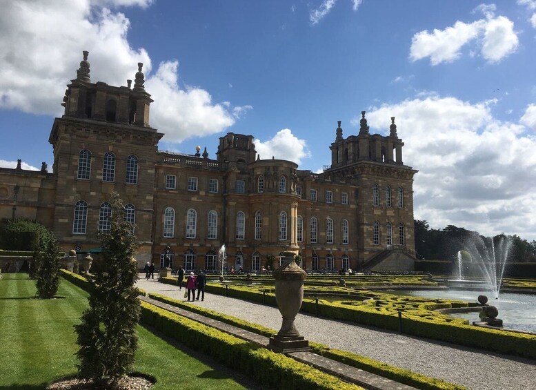 A grand historic building with a formal garden and a fountain. 3