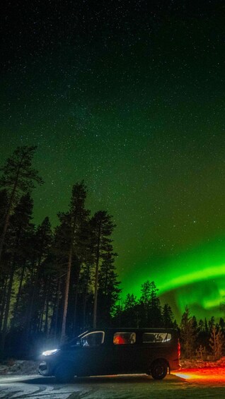 A vehicle parked on a road with a visible aurora borealis in the background. 2
