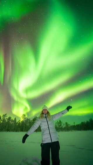 A person standing with arms outstretched under the Northern Lights. 4