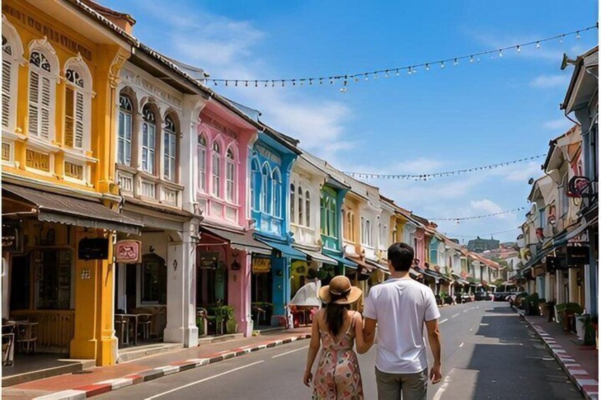 A street lined with colorful buildings, a couple walking, and a clear sky. 2