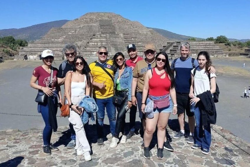A group of people standing in front of a large pyramid-like structure. 5