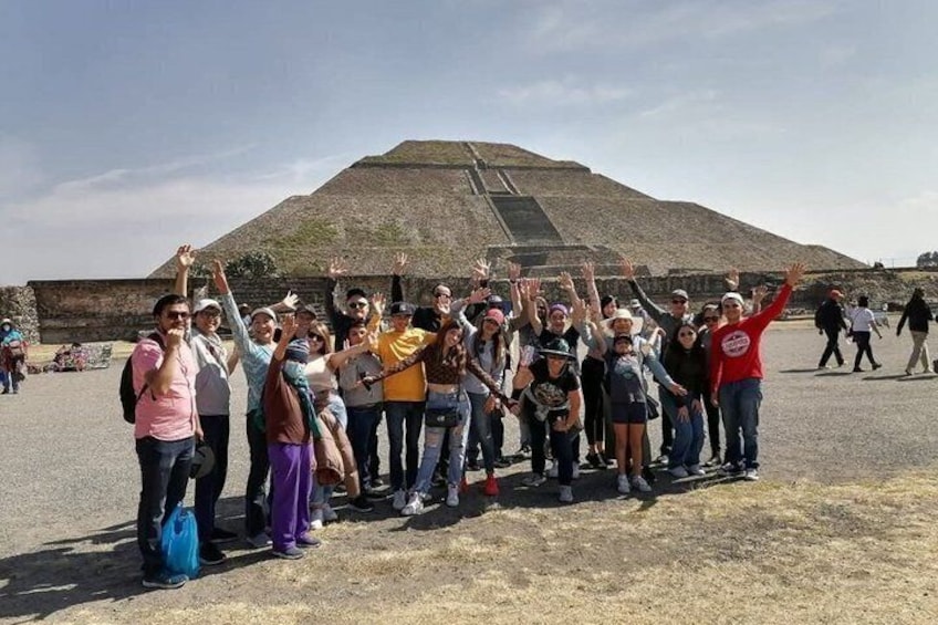 A group of people standing in front of a large pyramid-like structure. 4