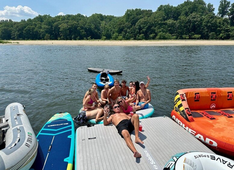 A group of people on a boat with inflatable rafts and a wakeboard. 1