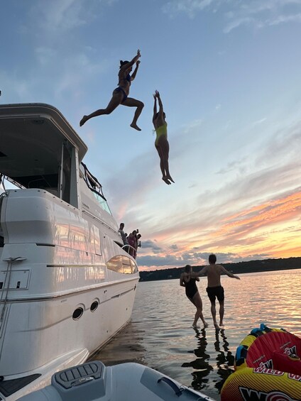 People jumping off a boat into the water at sunset. 3