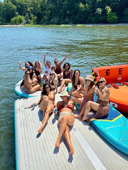 A group of people on a boat with inflatable rafts, surrounded by water and greenery. 5