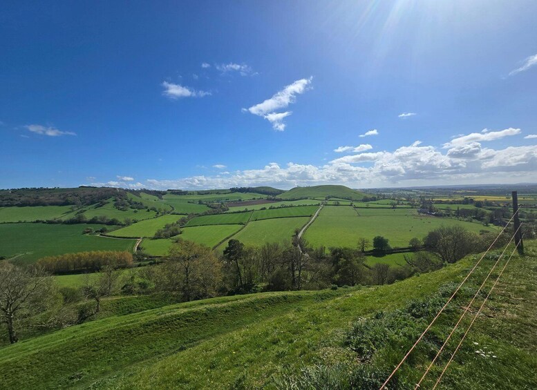 Rolling green hills, a clear blue sky, and distant fields. 3