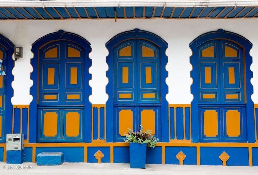 A building with three blue doors and yellow accents, located in Pijao, Quindio. 3