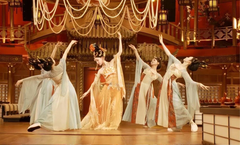 A stage with dancers in traditional costumes performing in a theater with ornate architecture and chandeliers. 4