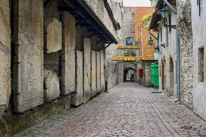 A cobblestone street with historic stone buildings, a green door, and a tiled roof. 2