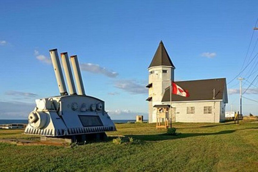 A large cannon, a white building with a red flag, and a tower. 5