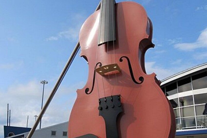 A large red violin sculpture in front of a building with a glass facade. 2