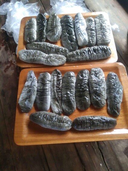 Two wooden cutting boards with rows of preserved fish. 5