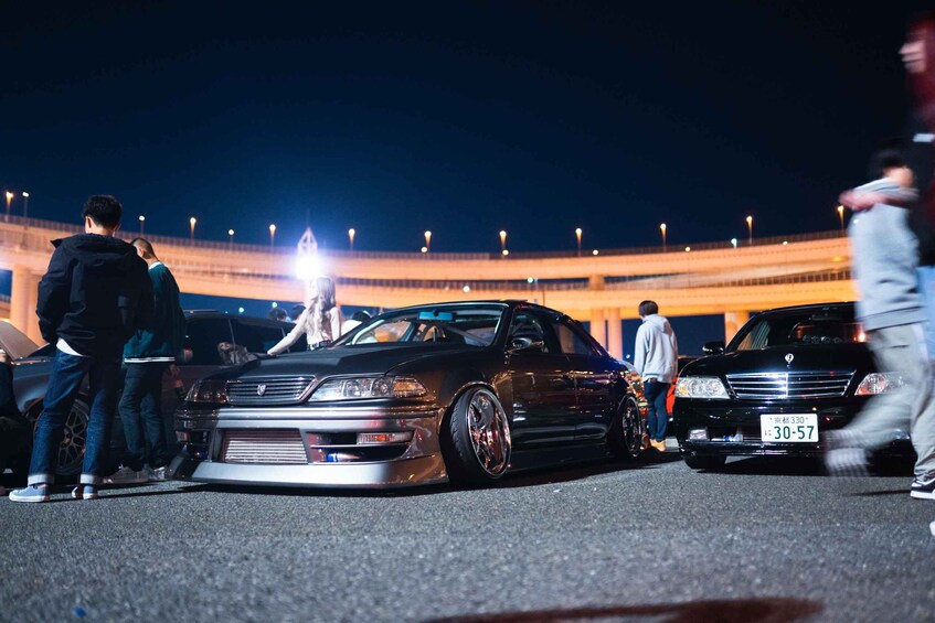 A modified car parked in a parking lot with a stadium in the background. 4