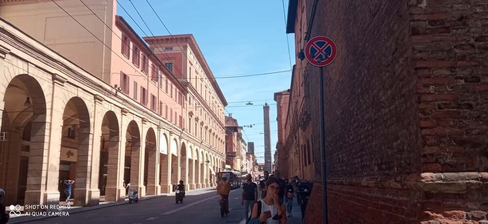 A street with historic buildings, a no parking sign, and pedestrians. 4