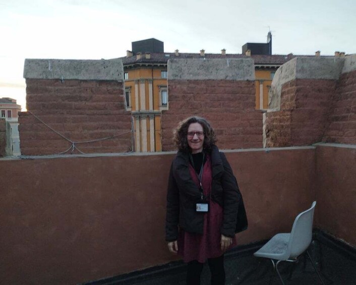 A person standing on a rooftop with brick walls and a chair. 5
