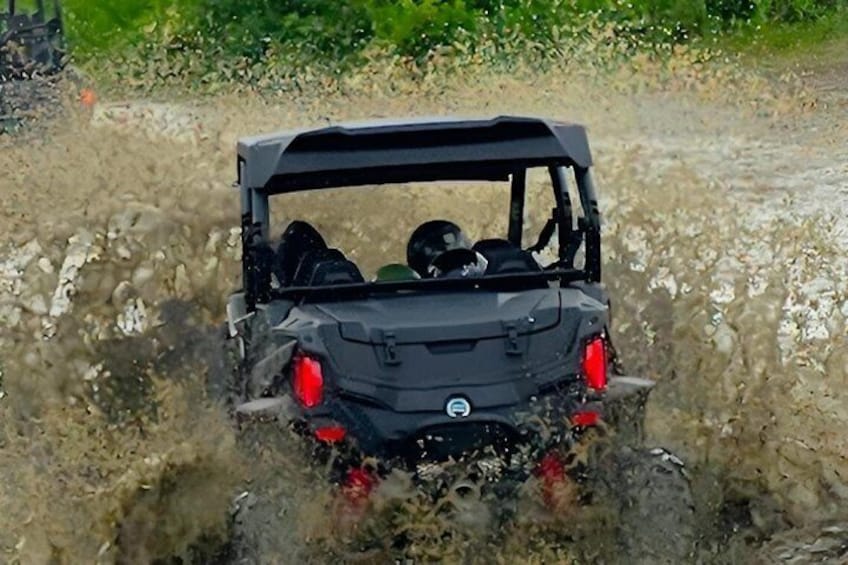 A vehicle driving through a muddy area with water splashing around. 5
