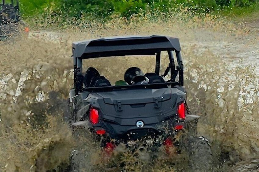 A vehicle driving through a muddy area with water splashing around. 5