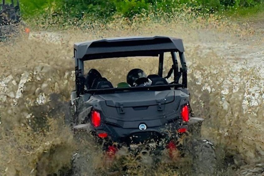 A vehicle driving through a muddy area with water splashing around. 2