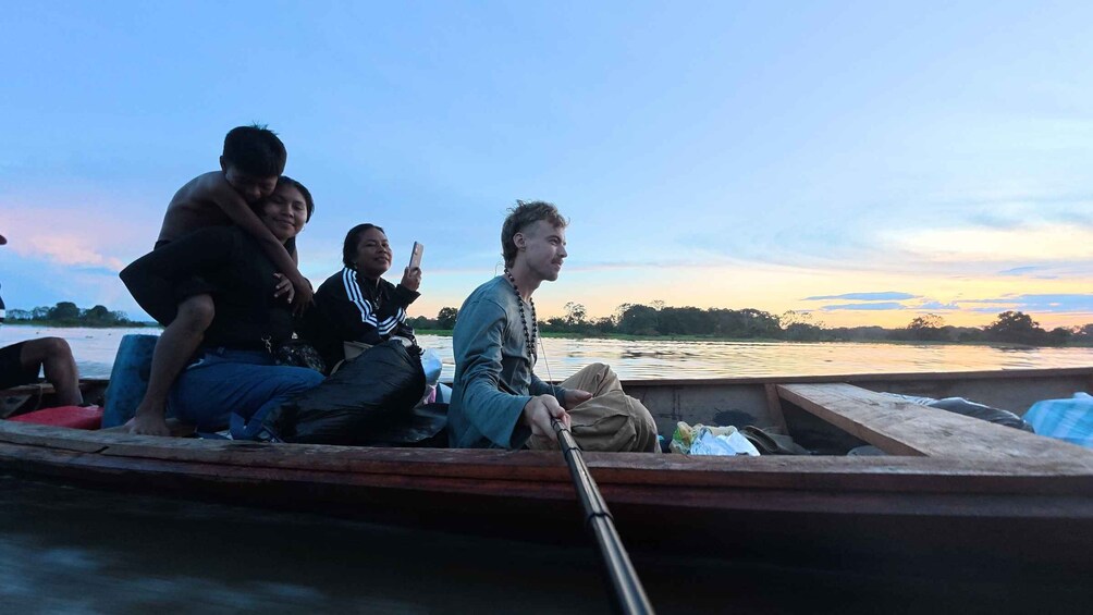 A group of people on a boat with a river and a sunset in the background. 2