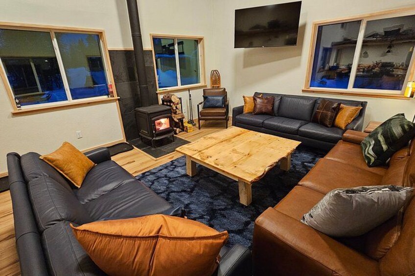 A modern living room with a fireplace, sofas, a coffee table, and large windows. 2
